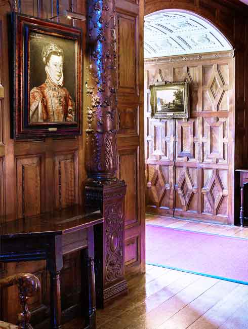 the carved inner hall of hever caslte with many hogarth classic picture lights